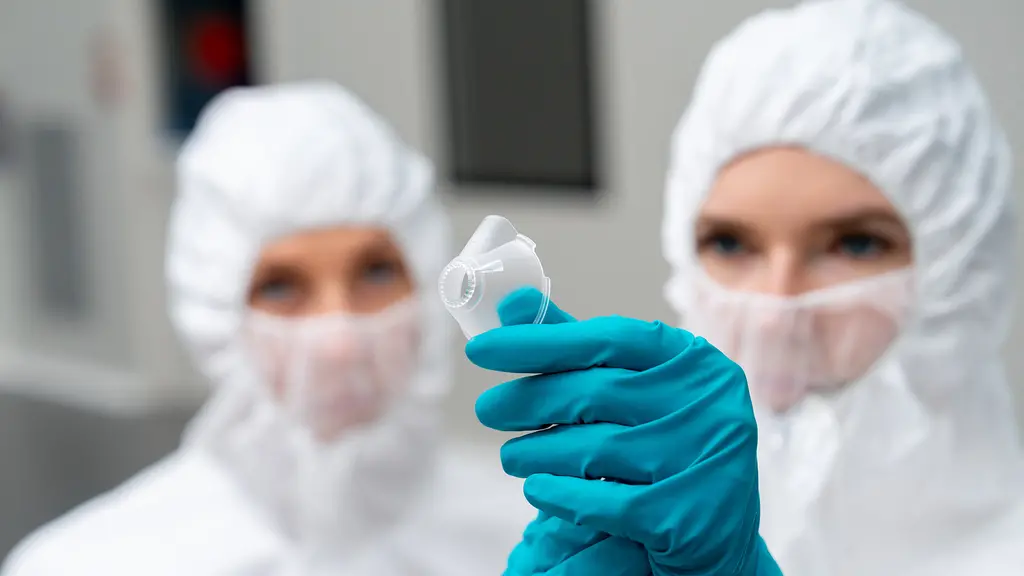 Two members of the cleanroom staff is inspecting a medical device.