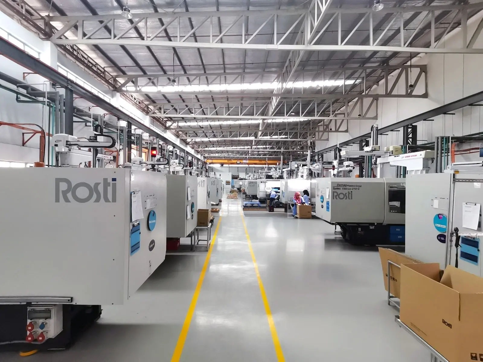 The Rosti Malaysia Workshop floor is grey with two yellow lines. Lots of Plastic injection moulding machines.