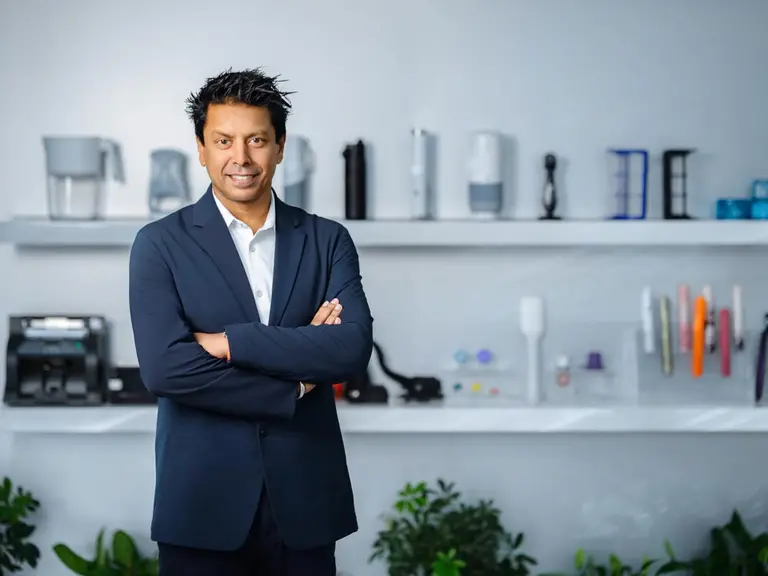 A confident man is standing in front of plastic injection moulded products