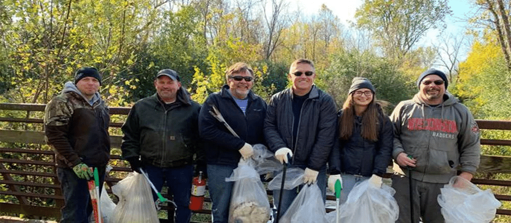 PCI employees hold garbage bags after a river clean up in Menomonee Falls