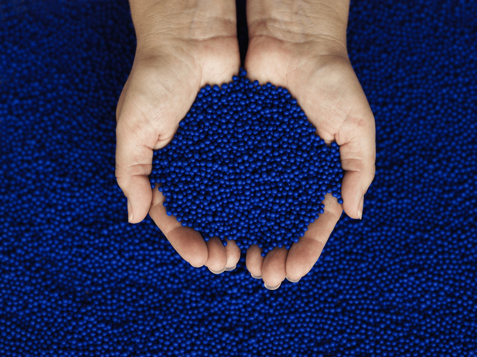 hands holdling blue plastic pellets