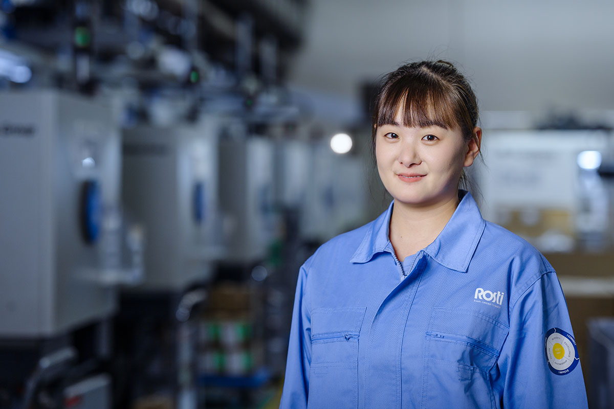 Chinese Rosti employee in front of several plastic injection moulding machines