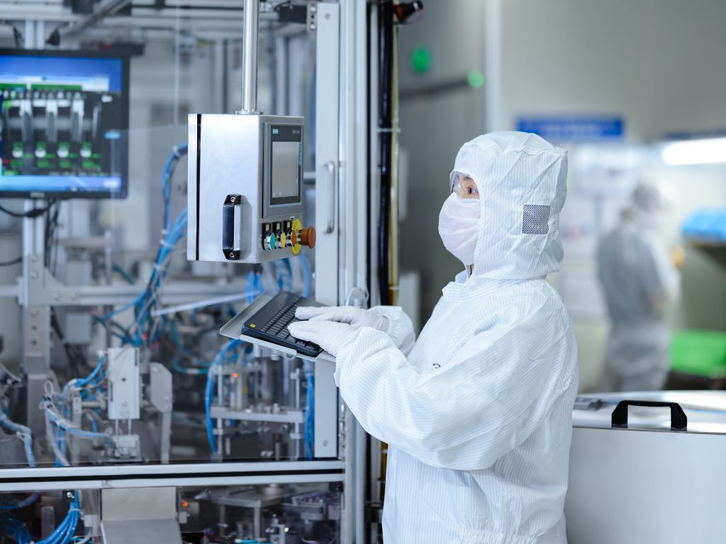 Cleanroom staff in white checking gear.